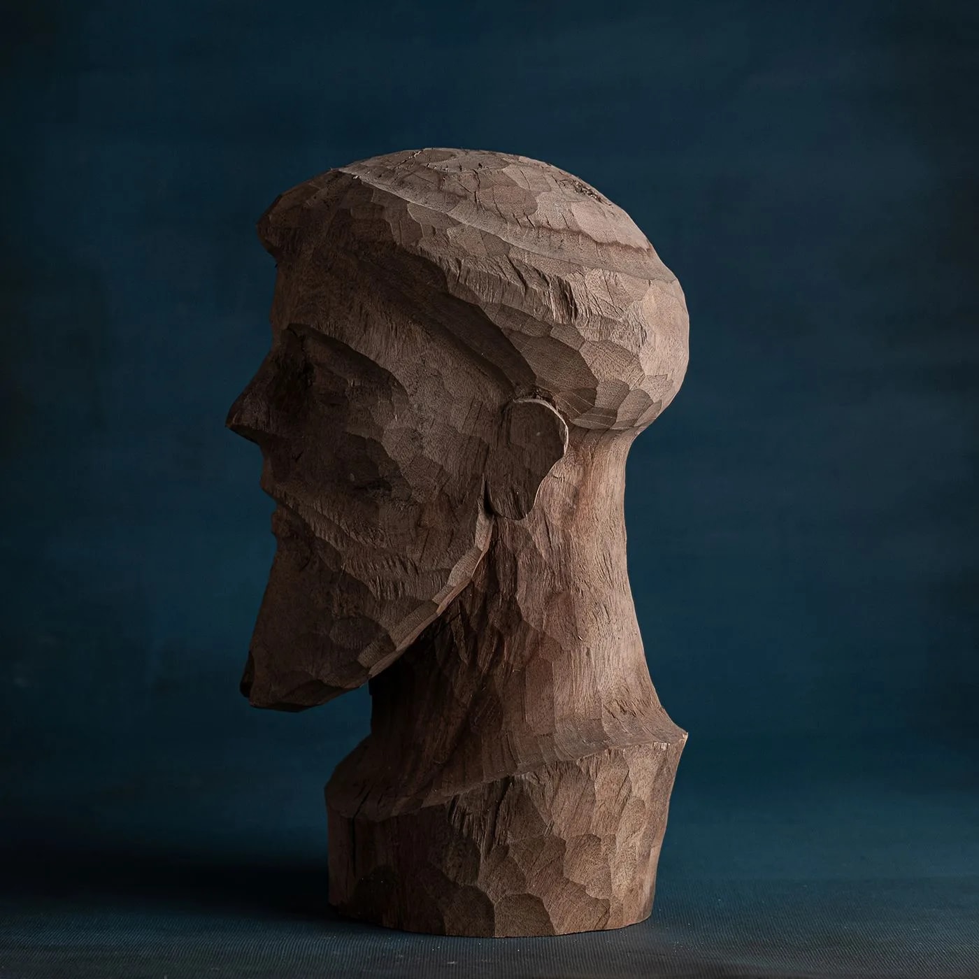 Rear three-quarter view of the wooden bust, highlighting the faceted back of the head and neck