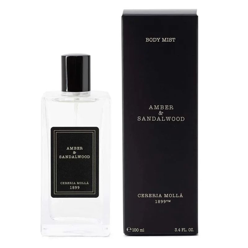 Amber and Sandalwood body mist bottle standing beside its slim black 100 ml box on white