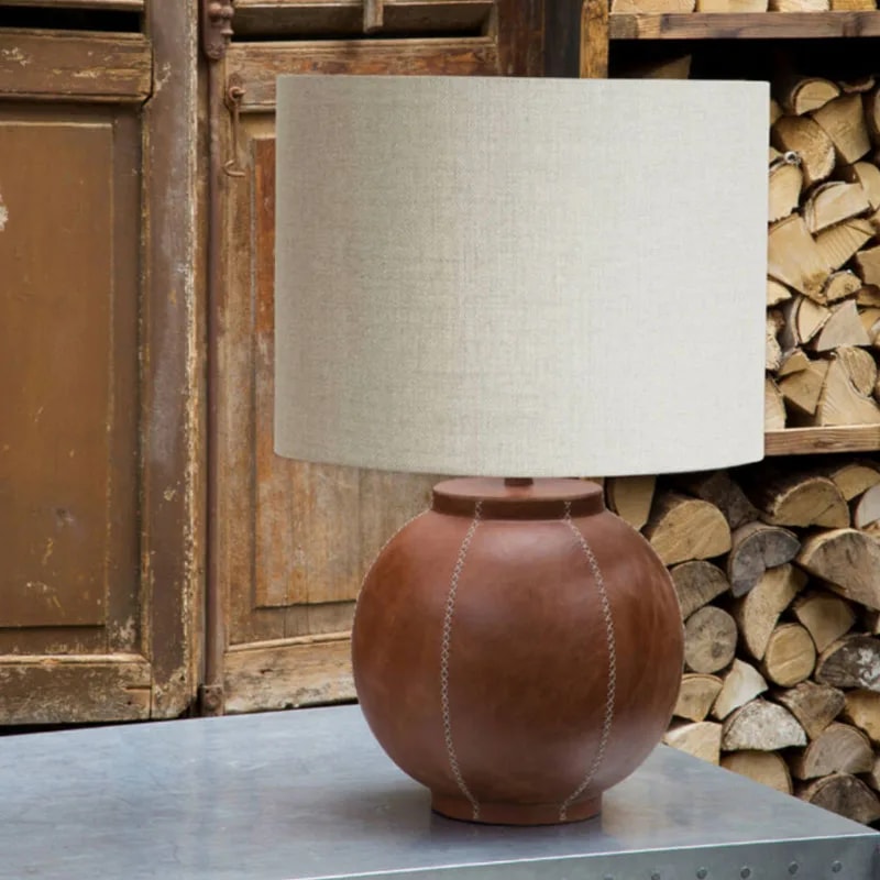 LIVIGNO cylinder shade on a terracotta ball lamp base, set on a metal table by stacked firewood