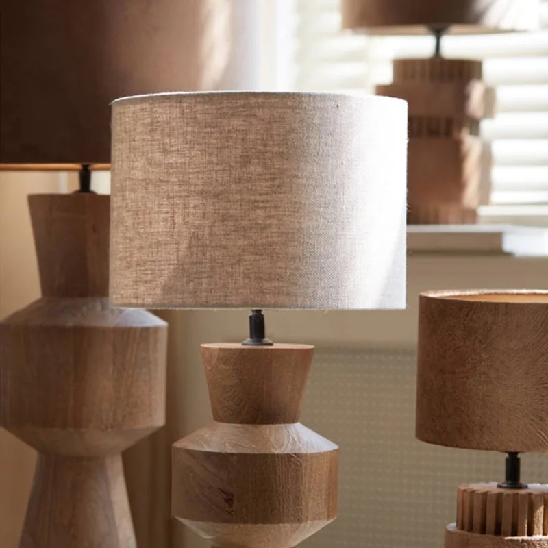 LIVIGNO natural linen shade on a pale turned wood lamp base among other lamps in a bright room