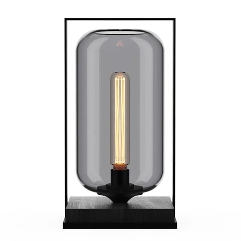 Tube Wood 40 table lamp with a smoked grey glass tube shade in a black frame and dark wood base, filament bulb lit