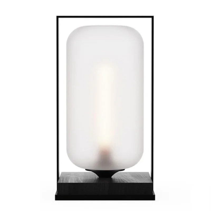 Tube Wood 40 table lamp with an opal white glass cylinder shade in a black frame on a black wood base, lit